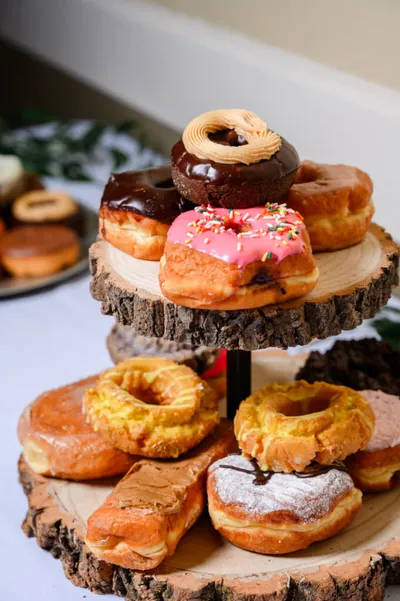 Assorted donuts on a two-tiered rustic wood slice stand
