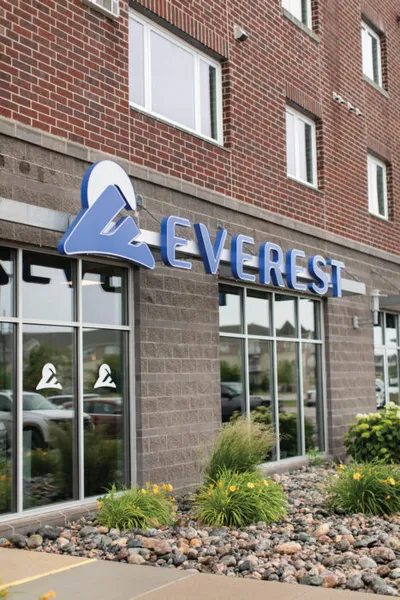 Everest sign with blue lettering on a brick building exterior with landscaping