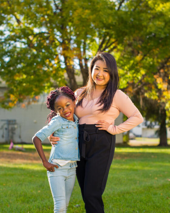Young girl and a young woman smiling together in a sunny park with autumn trees