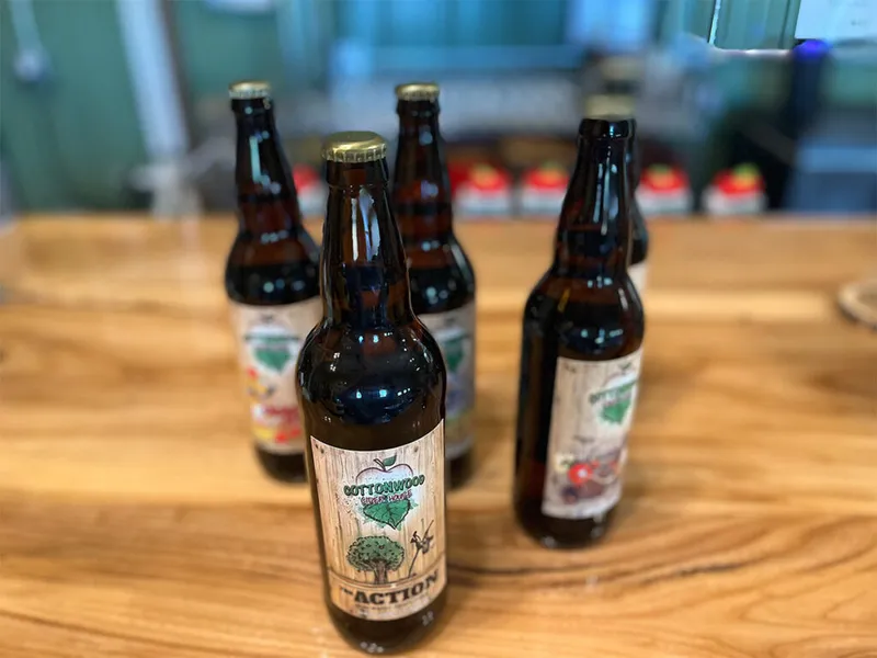 Amber glass bottles with Cottonwood Green Hop labels arranged on a wooden table
