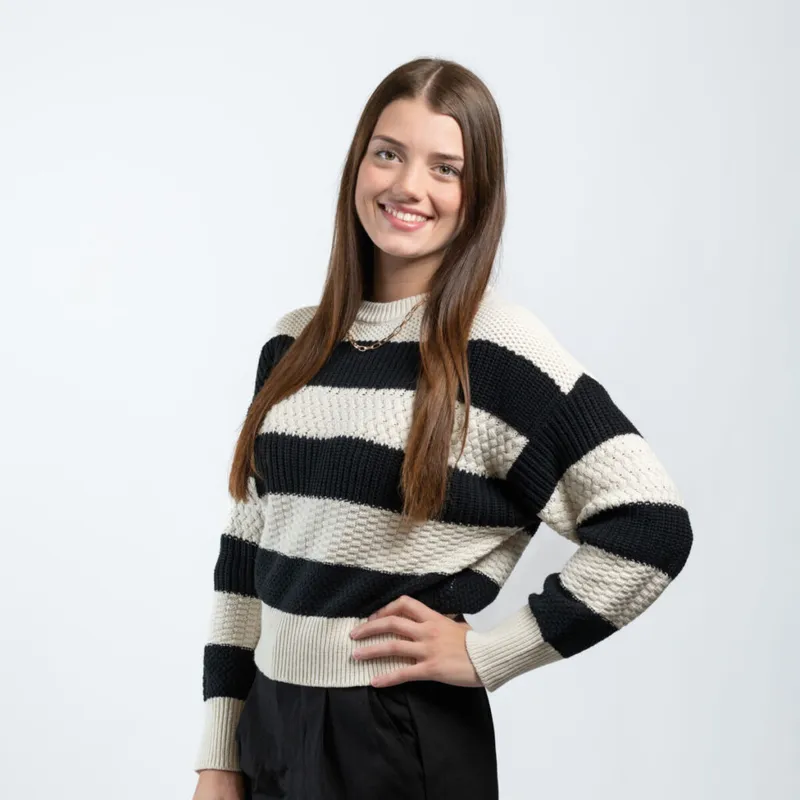 Smiling young woman with long brown hair wearing a black-and-cream striped knit sweater