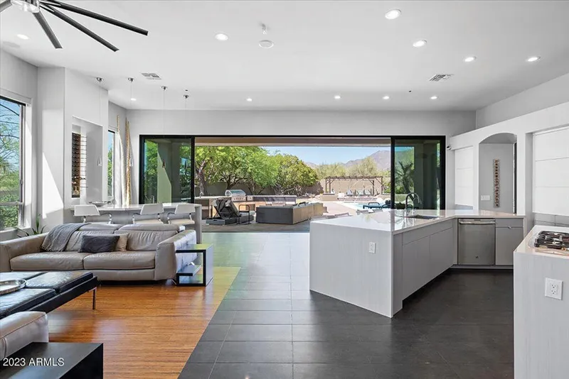 Open-plan living area and kitchen island opening to a pool patio with mountain views beyond