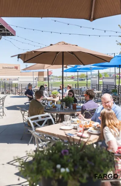Diners at shaded outdoor patio tables on a sunny day