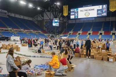Volunteers sorting food donations inside a large arena during a Fill the Dome event