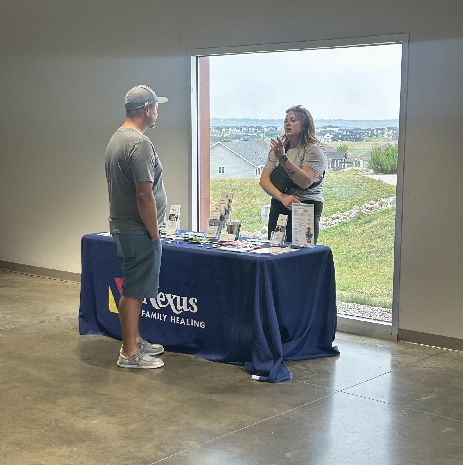 A Nexus Family Healing team member talking with a visitor at a Nexus information table