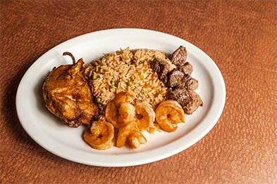 White plate with seasoned shrimp, roasted chicken, dirty rice, and grilled meat chunks