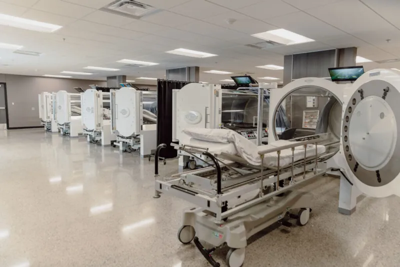 Row of hyperbaric oxygen chambers with hospital beds in a clinical treatment room