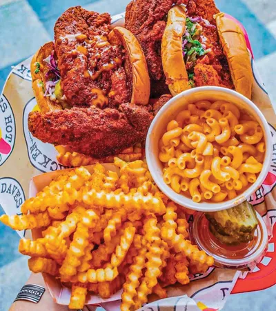 Spicy fried chicken sandwiches with crinkle fries and a cup of mac and cheese on a paper-lined tray