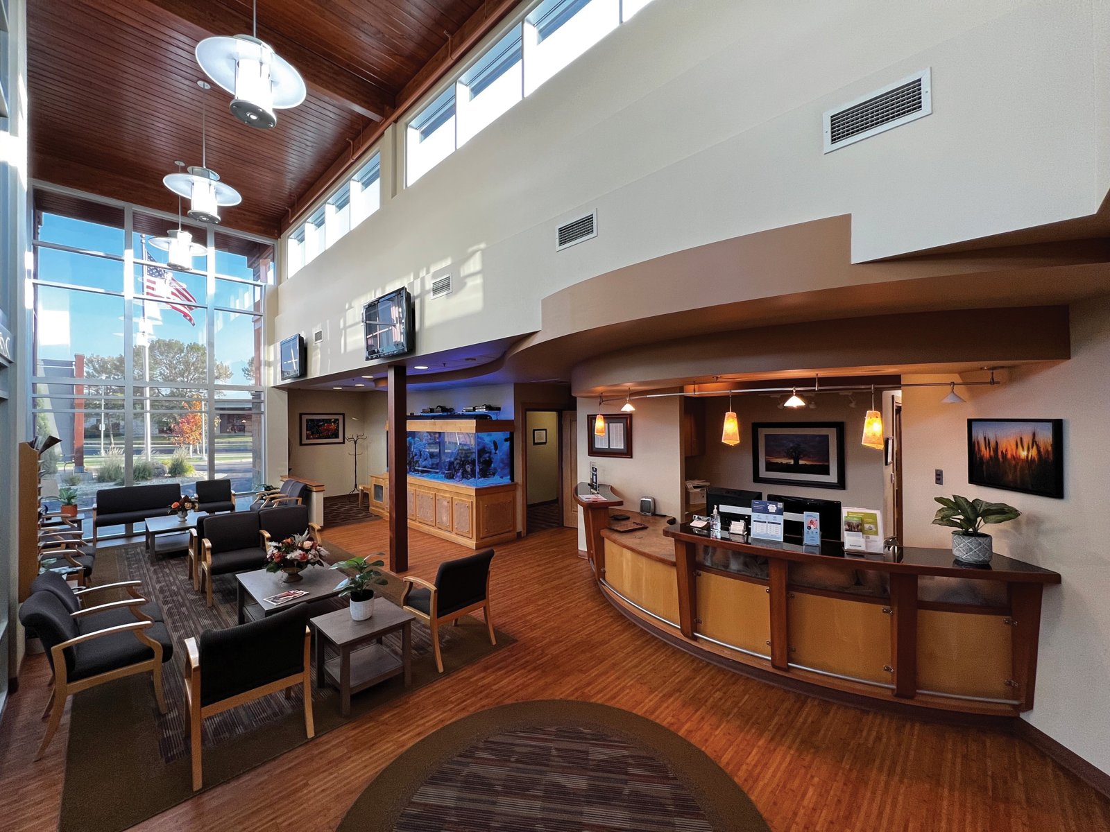 The bright waiting area at Prairie Oral and Facial Surgery with tall windows, wood ceiling, seating and a curved front desk