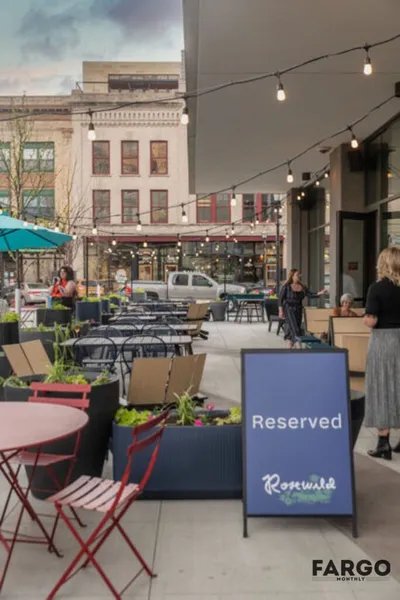 Outdoor restaurant patio with string lights, planters, and a Reserved sign for Rosewild