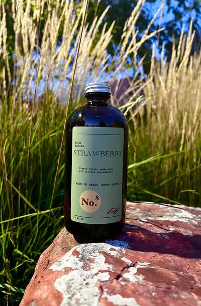 Dark glass bottle of Strawberry No. 8 simple syrup on a red rock outdoors