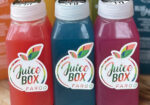 Three colorful bottled juices labeled Juice Box lined up side by side