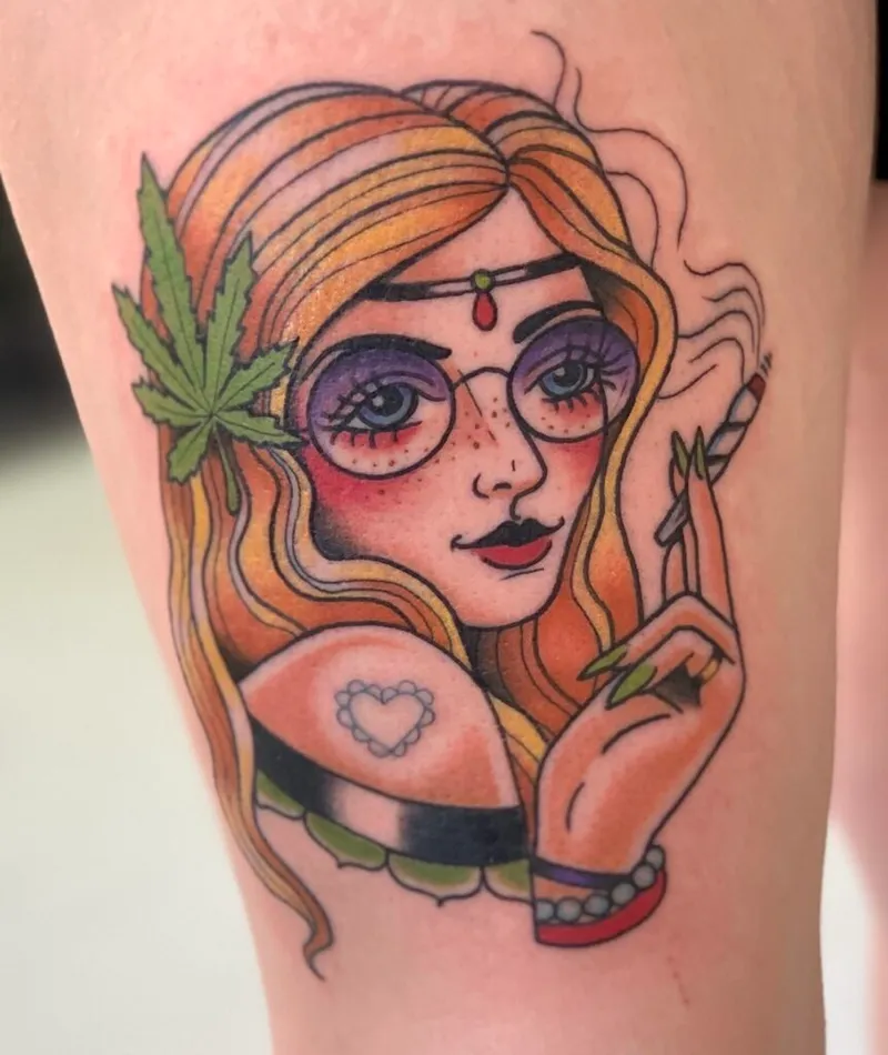 Colorful tattoo on a leg depicting a freckled woman with round purple glasses, red bindi, cannabis leaf, and a joint