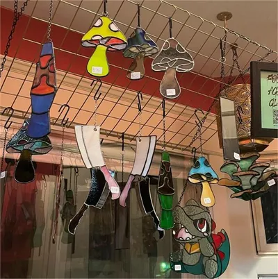 Colorful stained glass mushroom and character ornaments hanging from a wire grid display