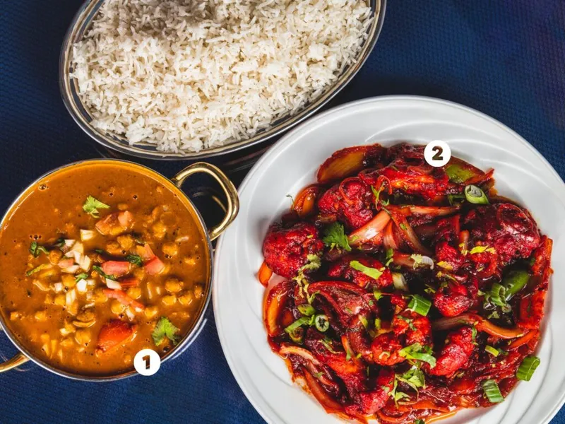 Overhead view of numbered dal curry, spiced red chili dish, and steamed rice on a dark blue surface