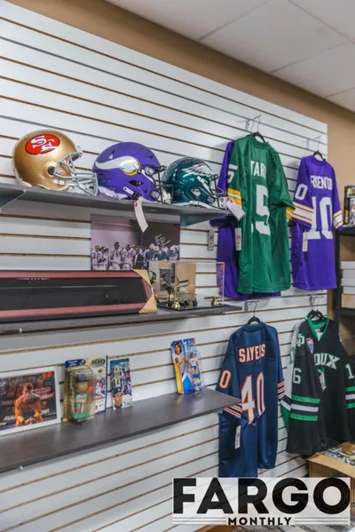 Sports memorabilia shop wall displaying NFL helmets and signed jerseys on slatwall shelving