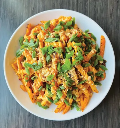 White bowl of cheesy loaded fries topped with green onions and breadcrumbs