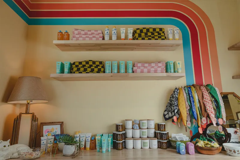 Retail shelves with checkered pouches and skincare products against a retro rainbow-striped wall