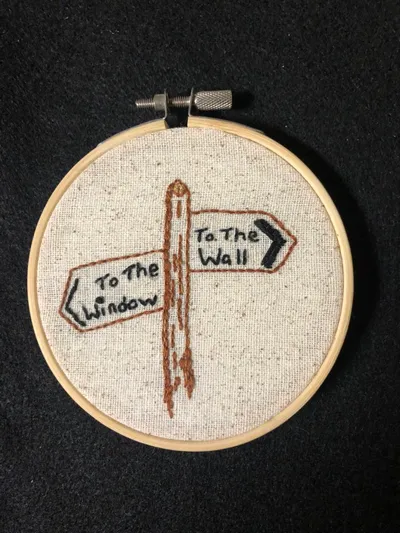 Embroidery hoop with two directional signs reading 'To The Window' and 'To The Wall