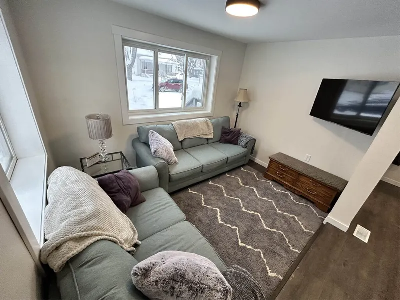 Cozy living room with two blue-gray sofas, patterned rug, and wall-mounted TV