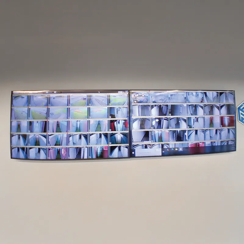 Two large monitors on a wall displaying a grid of security camera feeds