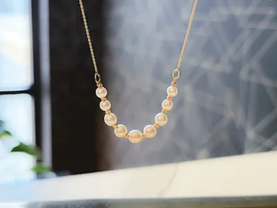 Delicate gold chain necklace with a curved row of cream pearls