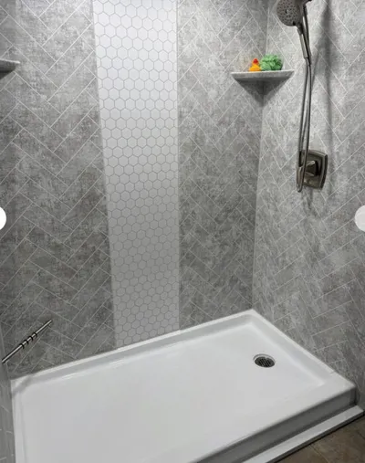 Walk-in shower with gray herringbone tile walls, hexagon accent strip, and white base