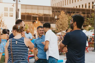 Small group of people laughing and socializing outdoors at a casual urban gathering