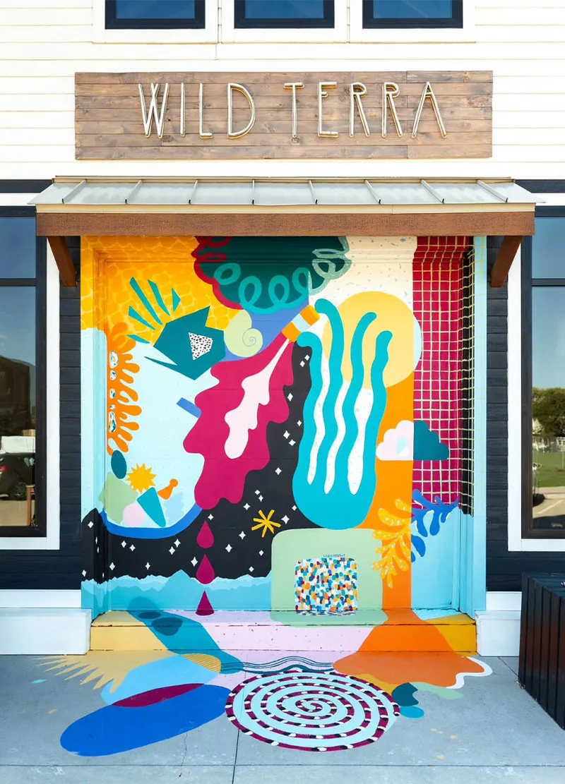 Vibrant abstract mural covering the entrance of a Wild Terra storefront, extending onto the sidewalk