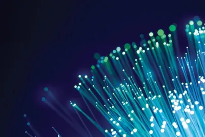 Bundle of glowing fiber optic strands with bright teal tips against a dark blue background