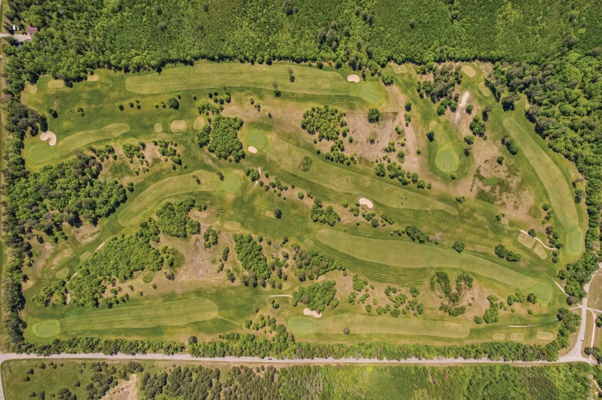 Aerial view of a wooded golf course with winding fairways and sand bunkers