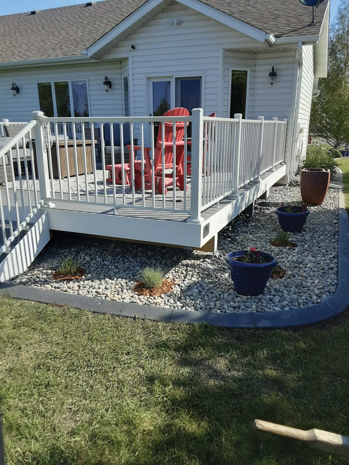 White deck with red Adirondack chairs beside a gravel garden bed with blue planters