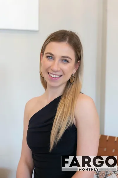 Smiling young woman with long blonde hair in a black one-shoulder top