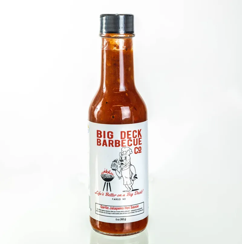 Big Deck Barbecue Co Garlic Jalapeño Hot Sauce in a glass bottle with red-orange sauce