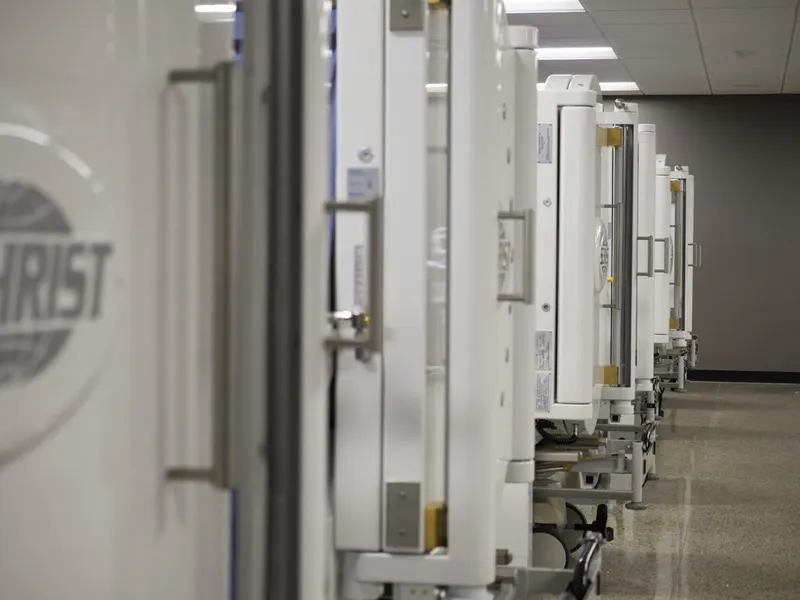 Row of white hyperbaric oxygen chambers lined up in a clinical facility hallway