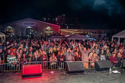 Large nighttime outdoor crowd at a concert in front of a Drekker building