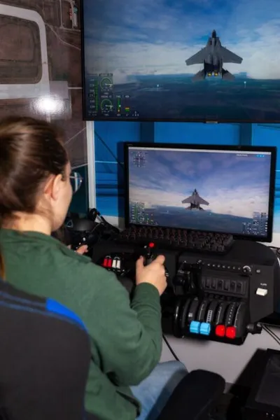 Person using a flight simulator joystick with dual jet fighter screens