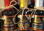 Three dark glass bottles with labels tied with twine on a market table