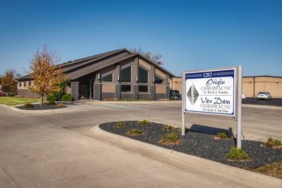 Exterior of Origin Chiropractic clinic with a roadside sign and A-frame building