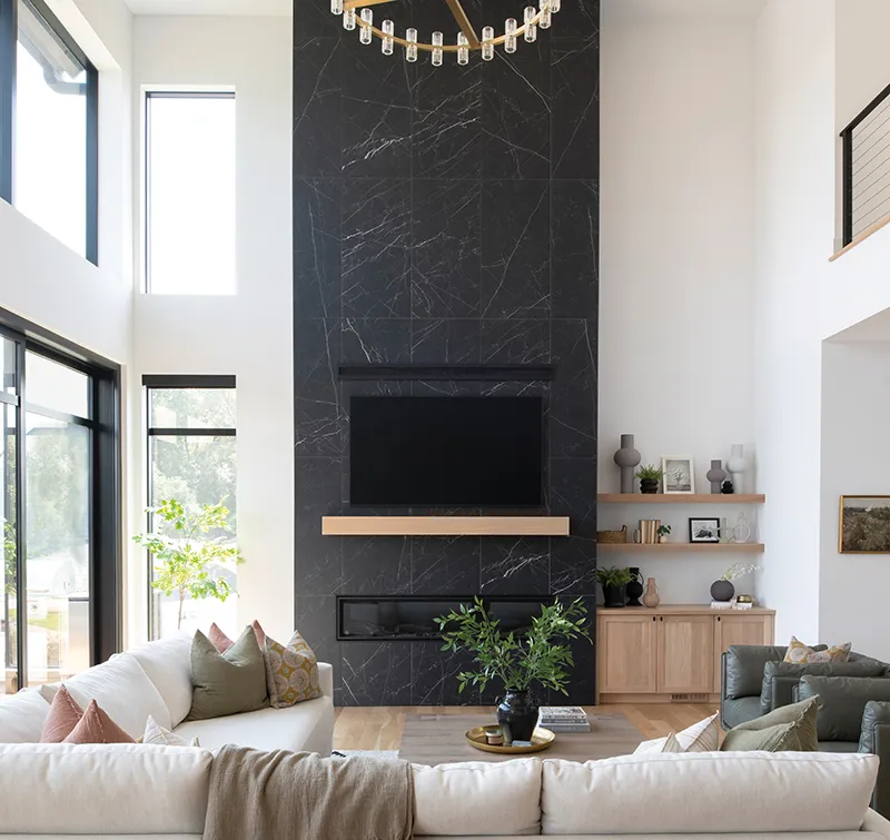 Modern living room with tall dark marble fireplace wall, wood mantel, and cream sectional sofa