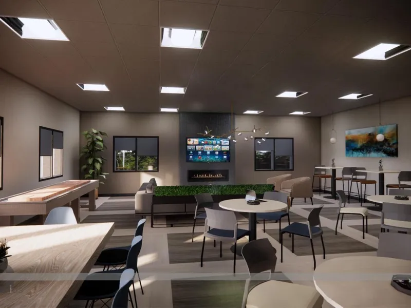 Modern lounge with round tables, chairs, a wall-mounted TV above a fireplace, and a shuffleboard table