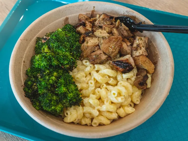 Bowl with mac and cheese, roasted broccoli, and grilled chicken chunks on a teal tray