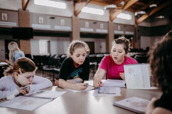Three girls studying together at a long table in a large indoor space