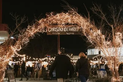 Lit archway with a Christkindlmarkt sign over a crowded outdoor night market