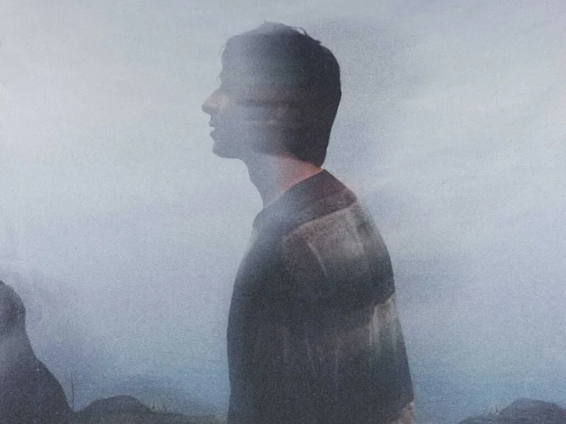 Man in profile silhouetted against a misty grey sky in a double-exposure portrait