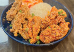 Crispy fried chicken strips over rice in a blue bowl with garnish