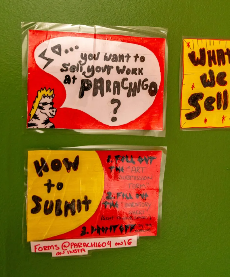 Hand-drawn red and yellow signs on a green wall reading 'So… you want to sell your work at Parachigo?' and 'How to Submit