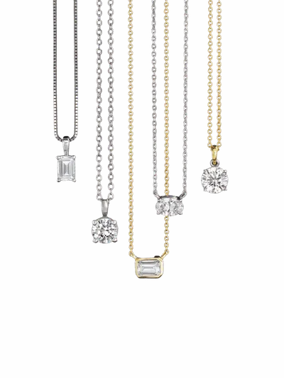 Five diamond pendants on silver and gold chains arranged against a white background