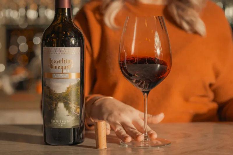 Kesselring Vineyards bottle and poured glass of red wine beside a cork on a bar