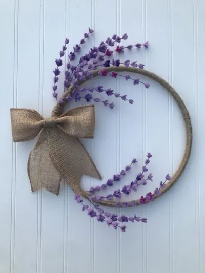 Circular wreath with purple felt wildflowers and a burlap bow on a white wall